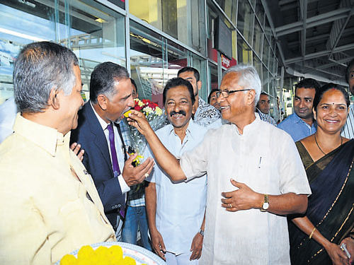 MLA J R Lobo offers sweets to Air India (Mangalore) Station Manager Nagesh Shetty before boarding the flight to Kuwait, at Mangalore International Airport on Monday. DH photo