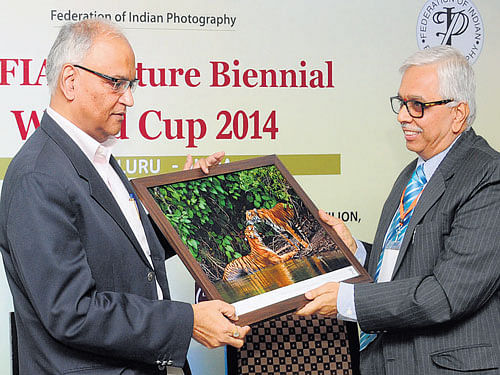 Federation Internationale de I'Art Photographique Chairman M N Jayakumar presents a photograph to Additional Chief Secretary (Tourism) Arvind Jadhav at the Inauguration of 17th FIAP Nature Biennial World Cup in the City on Wednesday. DH photo