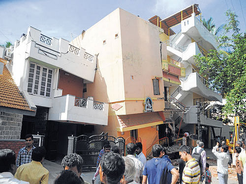 The three-storey building leans against the neighbouring building near Shankar Mutt in Basaveshwaranagar on Thursday. DH Photo