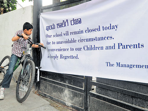 A student of The Indiranagar Cambridge School looks at a banner announcing that the institution is closed on Friday. DH photo/ Ranju P