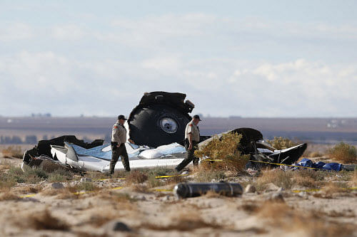 Sheriff's deputies look at a piece of debris near the crash site of Virgin Galactic's SpaceShipTwo near Cantil, California November 1, 2014. Virgin Galactic founder Richard Branson said on Saturday he was working with U.S. authorities to determine what caused a passenger spaceship being developed by his space tourism company to crash in California, killing one pilot and injuring the other. REUTERS