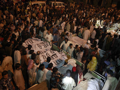 Pakistani relatives gather beside the covered bodies of victims who were killed in suicide bomb attack in Wagha border near Lahore November 2, 2014. At least 45 people were killed on Sunday when a suicide bomber blew himself up on the Pakistani-Indian border, police said, just after a daily ceremony when troops from both sides simultaneously lower the two nations' flags. REUTERS