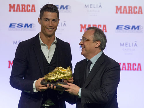 Real Madrids Cristiano Ronaldo (L) receives his Golden Boot trophy from Real Madrids president Florentino Perez during a ceremony in Madrid November 5, 2014. Ronaldo shares the trophy with Barcelona's Luis Suarez with a goal tally of 31 goals in Europe's domestic leagues last season. REUTERS photo