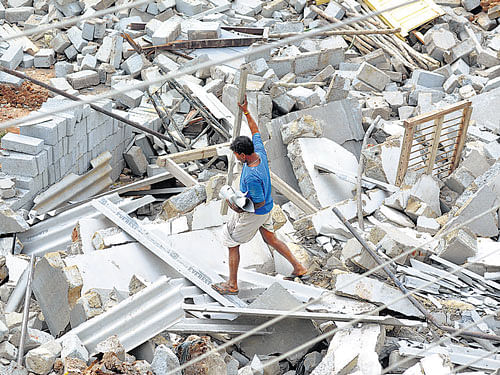 A man picks the leftovers fromthe site where a commercial establishment stood before it was demolished. DH PHOTO