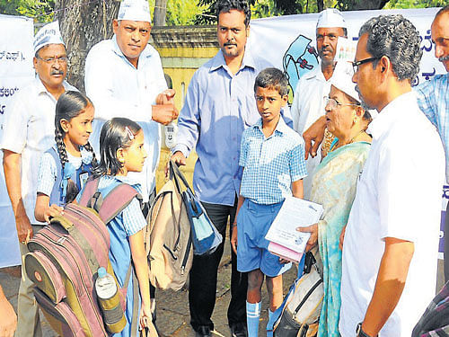 weighty issue: Members of People's Legal Forum and Aam Aadmi party compare the weight of children and their school bags, as part of a survey, in Mysore, on Monday. dh photo