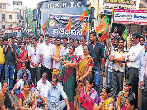 BJP workers protest demanding cut in bus ticket fares following cut in diesel price, by stopping a bus, in front of KSRTC&#8200;bus stand in Udupi on Monday. dh photo