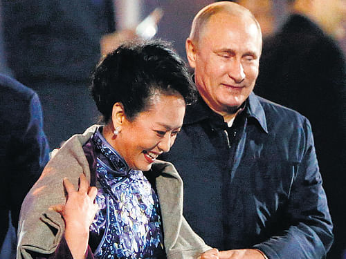 Russia's President Vladimir Putin puts a shawl around Peng Liyuan, wife of Chinese President Xi Jinping, as they arrive to watch a fireworks show after a welcome banquet for the Asia Pacific Economic Cooperation summit in Beijing. AP