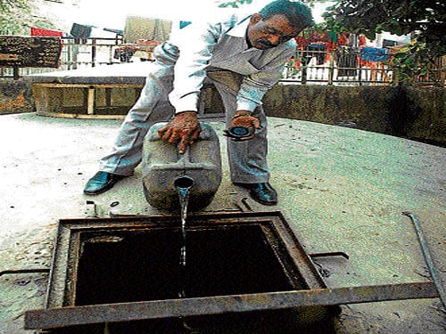 A DJB worker pours chlorine in a water supply unit to purify water.