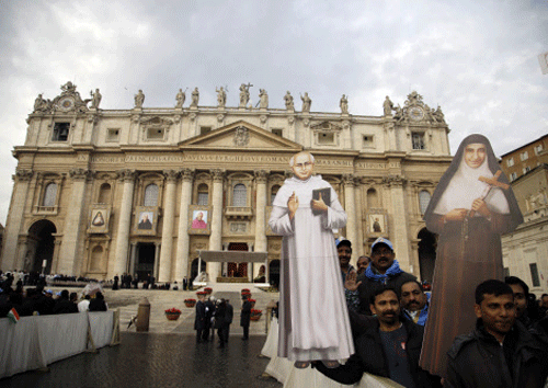 Faithfuls hold cardboard cutouts of sister Eufrasia Eluvathingal, right, and priest Elias Chavara in front of St. Peter's Basilica prior to the start of their Canonization Mass celebrated by Pope Francis in St. Peter's Square, at the Vatican, Sunday, Nov. 23, 2014. AP PHOTO