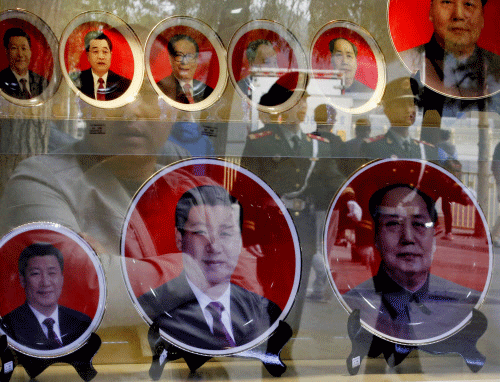 Paramilitary policemen and pedestrians are reflected in a window of a shop selling souvenirs bearing the pictures of China's President Xi Jinping and former leaders near the Great Hall of the People in Beijing in this October 23, 2014 file photo Reuters