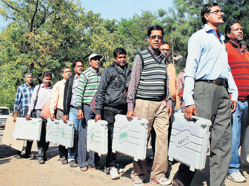 Polling officials carry Electronic Voting Machines before leaving for their polling stations in Jamshedpur on Sunday.  PTI