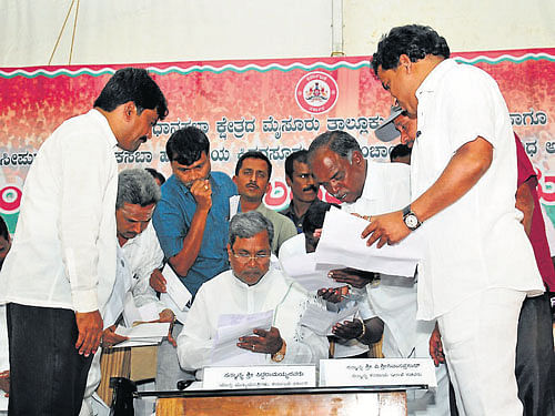Chief Minister Siddaramaiah besieged by people with grievances, at his maiden 'Janasamparka Sabhe', at Varuna village, in Mysuru taluk, on Tuesday. DH PHOTO