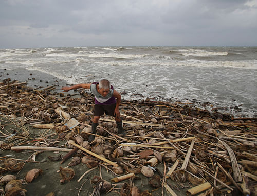 A man throws wood along the shore as strong waves from Typhoon Hagupit hit Atimonan, Quezon province, eastern Philippines on Saturday, Dec. 6, 2014. A wide swath of the Philippines, including the capital Manila, braced Friday for a dangerously erratic and powerful typhoon approaching from the Pacific, about a year after the country was lashed by Typhoon Haiyan that left more than 7,300 people dead. AP Photo