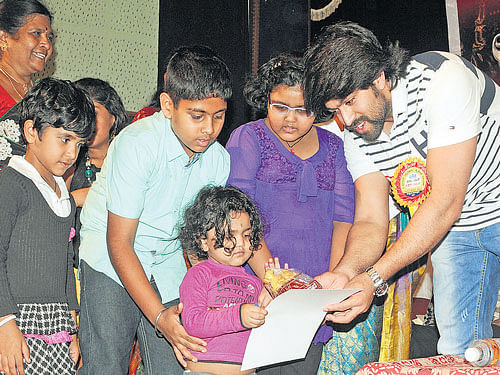 Actor Yash presents an award to a child at the cultural festival organised by the Lalita Kala Sangha of The Printers (Mysore) Private Limited in the City on Sunday. DH PHOTO