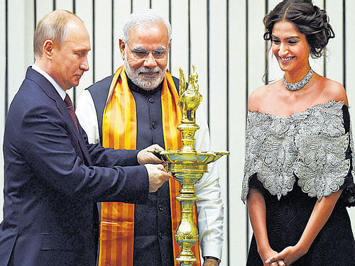 Prime Minister Narendra Modi with Russian President Vladimir Putin lights a lamp as actor Sonam Kapoor looks on during theWorld Diamond Conference in NewDelhi on Thursday. PTI