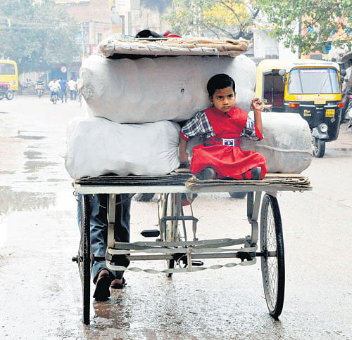 Aschoolgirl rideshomeona tricycle, shelteredfromthe rainfall that lashed Hosapete in Ballari districtonFriday. KPN