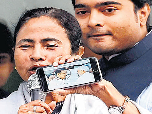 Mamata Banerjee shows a photo of Prime Minister Narendra Modi with Sahara owner Subrata Roy in Kolkata on Saturday. PTI
