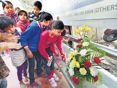 Girls pay tributes to the December 16 Delhi gang-rape victim on the eve of second  anniversary of the incident, at a bus stop in New Delhi on Monday. PTI Photo