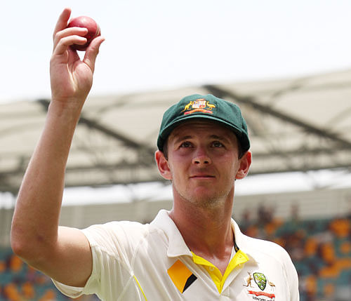 Australian bowler Josh Hazlewood holds the ball aloft after taking five wickets on debut during play on day two of the second cricket test against India in Brisbane, Australia, Thursday, December 18, 2014. AP Photo