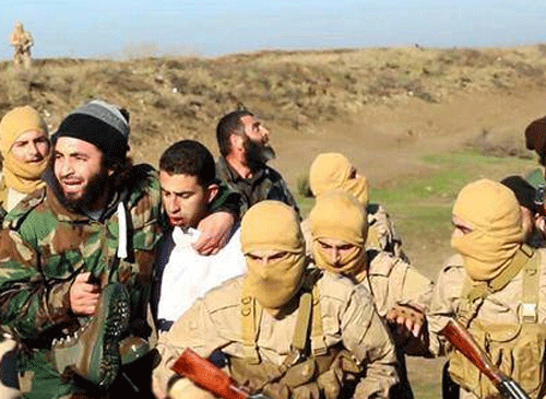 This image posted by the Raqqa Media Center of the Islamic State group, a militant extremist group, which has been authenticated based on its contents and other AP reporting, shows members of the Islamic State group while captured the pilot, center, wearing a white shirt in Raqqa, Syria, Wednesday, Dec. 24, 2014. Activists say that Islamic State fighters have shot down a warplane believed to be from the U.S.-led coalition over Syria. AP Photo
