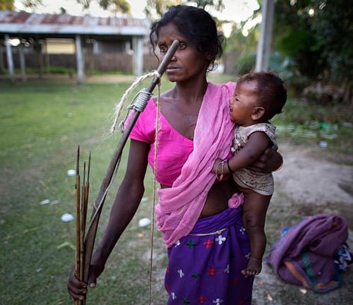 Scores of protests were on Wednesday taken out against the killing of 68 persons in an NDFB assault and alleged police firing in Assam. A tribal woman with her child and bow and arrows arrives at a make shift relief center in a local school after her village was attacked by an indigenous separatist group called the National Democratic Front of Bodoland, in Shamukjuli village in Sonitpur district of Indian eastern state of Assam. AP image