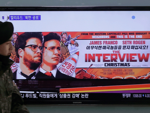 South Korean army soldier walks near a TV screen showing an advertisement of Sony Picture's 'The Interview,' at the Seoul Railway Station in Seoul, South Korea.