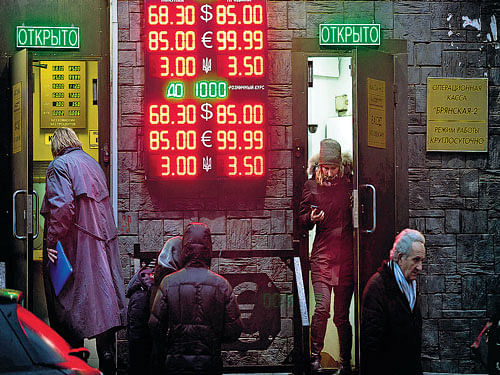 severe crisis: People wait to exchange their currency as  signs advertise the exchange rates at a currency exchange office in Moscow, Russia. The Russian ruble came under intense selling pressure, falling at one point by a catastrophic 20 per cent to a new historic low. Photo: AP