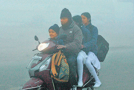 Children go to school in the early morning fog in Gurgaon. PTI