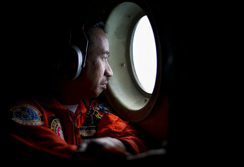 A member of an Indonesian Hercules C130 aircrew watches through a window while monitoring the Belitung Timur sea during search operations for AirAsia flight QZ8501 near Belitung island, December 29, 2014 in this photo taken by Antara Foto. REUTERS