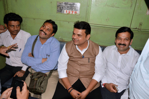 Maharashtra Chief Minister Devendra Fadnavis interacts with commuters while traveling on a suburban train from Chhatrapati Shivaji Terminus (CST) to Kalyan on Monday. PTI Photo