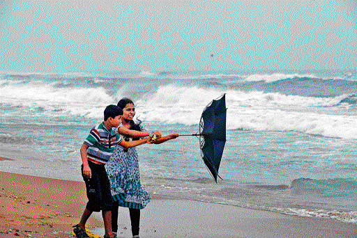 Children try to fold an umbrella which turned inside out at Marina beach in Chennai. DH PHOTO