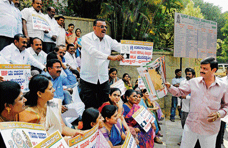 Unperturbed: MLA Muniratna distributes calendars to BJP members who were staging a a protest against him in front of the BBMP building on Wednesday. DH photo