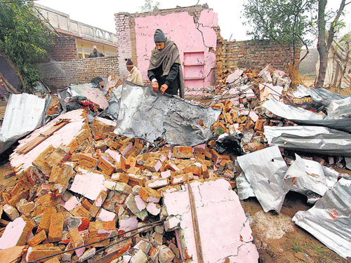 A villager looks through the debris of his house damaged by the firing from across the border by Pakistani forces, at a Village in Samba district of Jammu on Tuesday.  pti