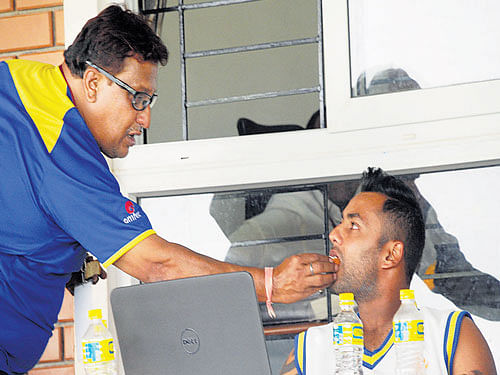 well done! Karnataka team's logistics manager Ramesh Rao gives sweets to Stuart Binny after the latter was named in India's World Cup team. DH photo