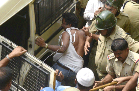 The Police trying to protect and whisk away the teacher accused of molesting a child from an angry mob at Hosaguddadahalli in Bengaluru on Wednesday. DH Photo.