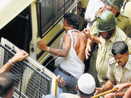 Police whisk away physical education teacher Ramakrishna as an unruly mob tries to go after him.