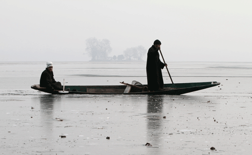 A Kashmiri boatman breaks the frozen surface of Dal Lake as they row past on a cold and foggy morning in Srinagar. Photo: AP