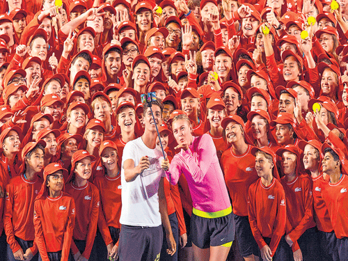 say cheese!: Tennis players Thanasi Kokkinakis and Maria Sharapova take a selfie with ball boys and girls preparing for the Australian Open in Melbourne. AFP