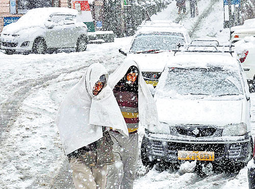Blanket of snowforms over the roads and vehicleswhile peoplewalk after snowfall in Dalhousie, Himachal Pradesh onWednesday. PTI photo