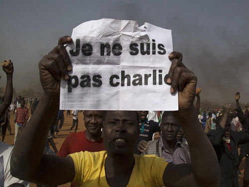A man holds a sign during a protest against Niger President Mahamadou Issoufou's attendance last week at a Paris rally in support of French satirical weekly Charlie Hebdo, which featured a cartoon of the Prophet Mohammad as the cover of its first edition since an attack by Islamist gunmen, in Niamey. Five people were killed in violent riots in Niger's capital with angry crowds setting fire to churches. Reuters photo