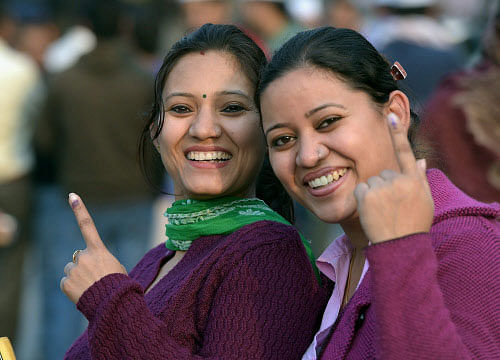 Women show their inked fingers after casting votes for Assembly elections at a polling station in East Delhi on Saturday. PTI Photo