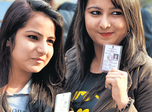 Youngwomen showtheir voter ID cards after excercising their franchise at a polling station in NewDelhi on Saturday. DH photo by Parivartan Sharma