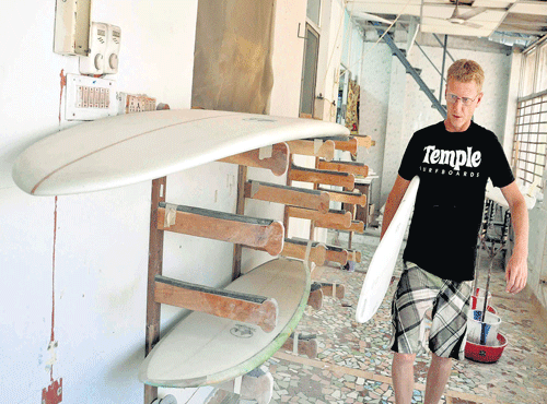 Dave shifts a polished surfboard to the next process at his factory at Mamallapuram.