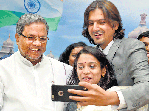 Ricky Kej (right) and his wife Varsha Kej click a selfie with Chief Minister Siddaramaiah, after he was felicitated for winning Grammy for his album 'Winds of Samsara', in Bengaluru on Monday. DH photo