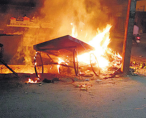 On the boil: A pushcart which was set afire during the violent clash that erupted in the course of a march taken by the Popular Front of India (PFI) in Shivamogga on Thursday. DH Photo