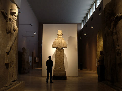 In this Nov. 24, 2009 file photo, a journalist looks at an Assyrian statue, center, in front of two Assyrian human-headed winged bulls at Iraq's national museum, in Baghdad. Islamic State militants 'bulldozed' the renowned archaeological site of the ancient city of Nimrud in northern Iraq on Thursday, March 5, 2015 using heavy military vehicles, the government said. AP photo