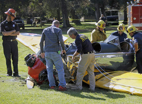 Investigators prepare to remove the World War II-era trainer airplane that actor Harrison Ford crash-landed Thursday at Penmar Golf Course in the Venice area of Los Angeles, AP photo