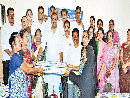 Minister for Health and Family Welfare U T Khader distributes free LPG stoves to the beneficiaries at Ullal City Municipal Council office on Wednesday. DH Photo