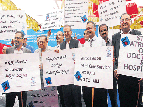spare us: Members of Private Hospital and Nursing Homes Association led by Dr Devi Shetty and Dr Sudarshan Ballal stage a protest at the Freedom Park on Monday against assaults on medical professionals. DH photo