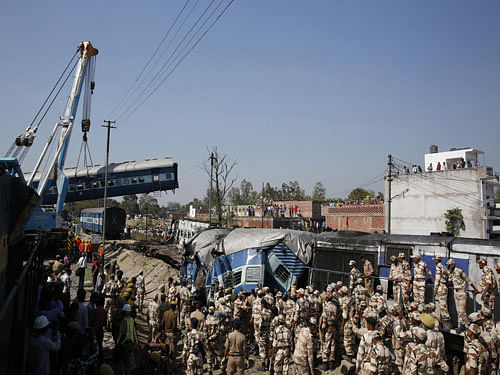 Rescue workers gather at the site of a train accident near Bachhrawan village in the northern Indian state of Uttar Pradesh, Friday, March 20, 2015. Police and rescue workers used gas cutters to rip apart the wreckage to find people who were feared to be trapped after three coaches of a passenger train derailed in northern India. Ap photo